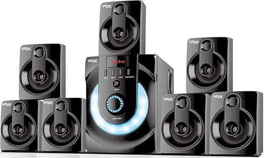 Vox V7171 Real 7.1 Bluetooth Home Theatre System – 90W Surround Sound with Subwoofer & 7 Satellite Speakers “Vox V7171 Real 7.1 Channel Bluetooth Home Theatre System featuring a central subwoofer with LED lighting and seven satellite speakers arranged around it, all in glossy black finish.”